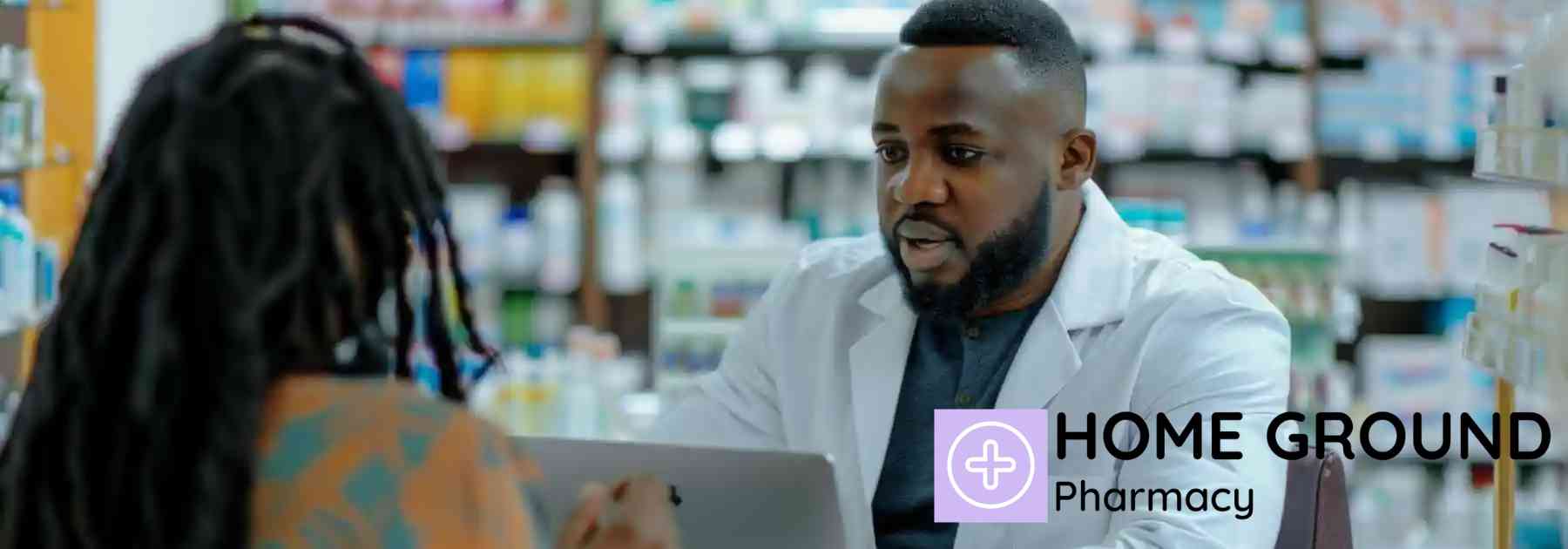 male pharmacist on laptop speaking with female patient