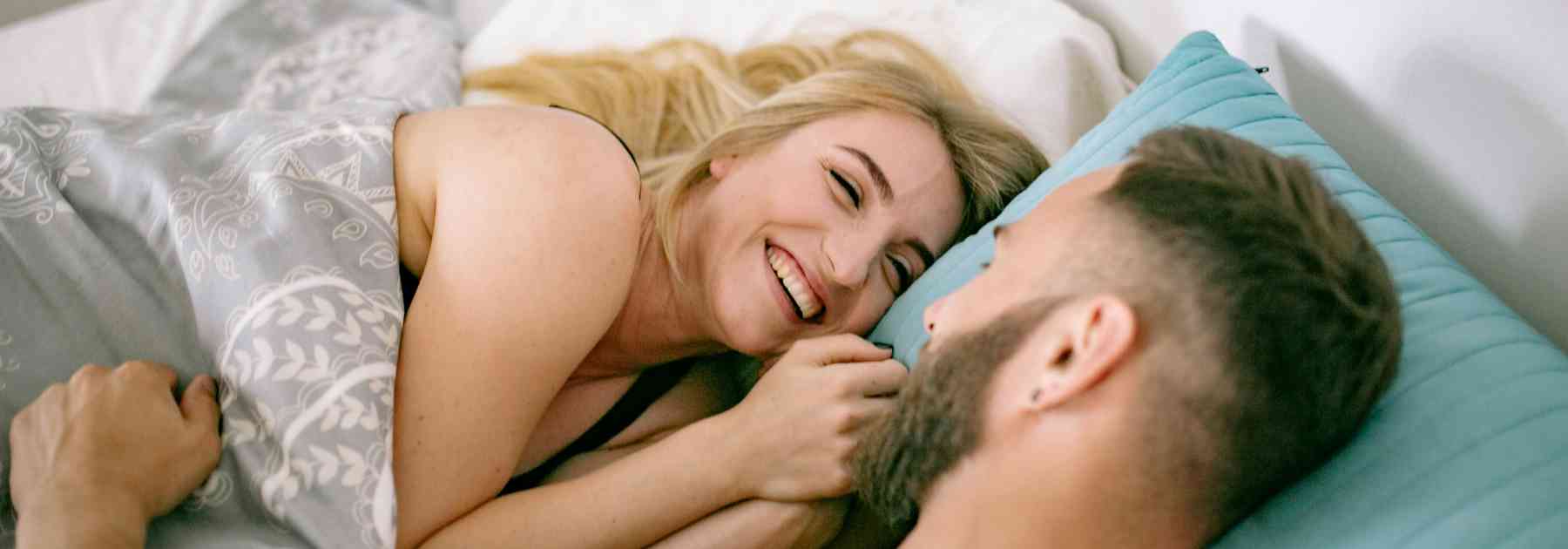 smiling couple lying in bed