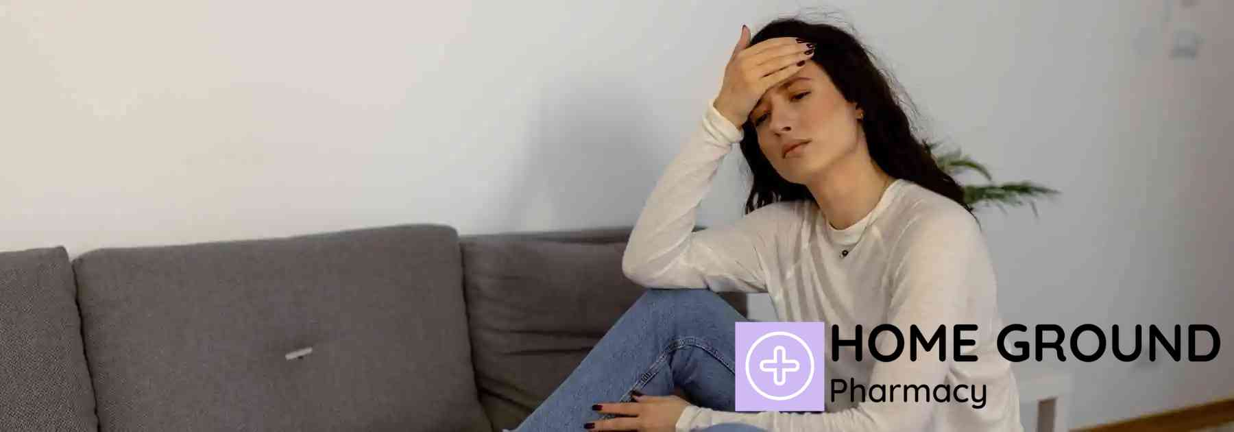 woman sitting on sofa holding her forehead in discomfort