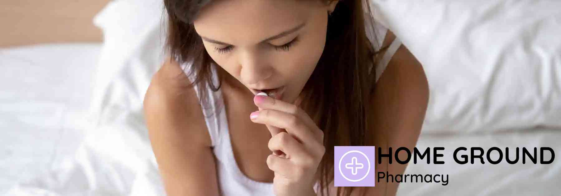 young woman sitting on bed taking white pill