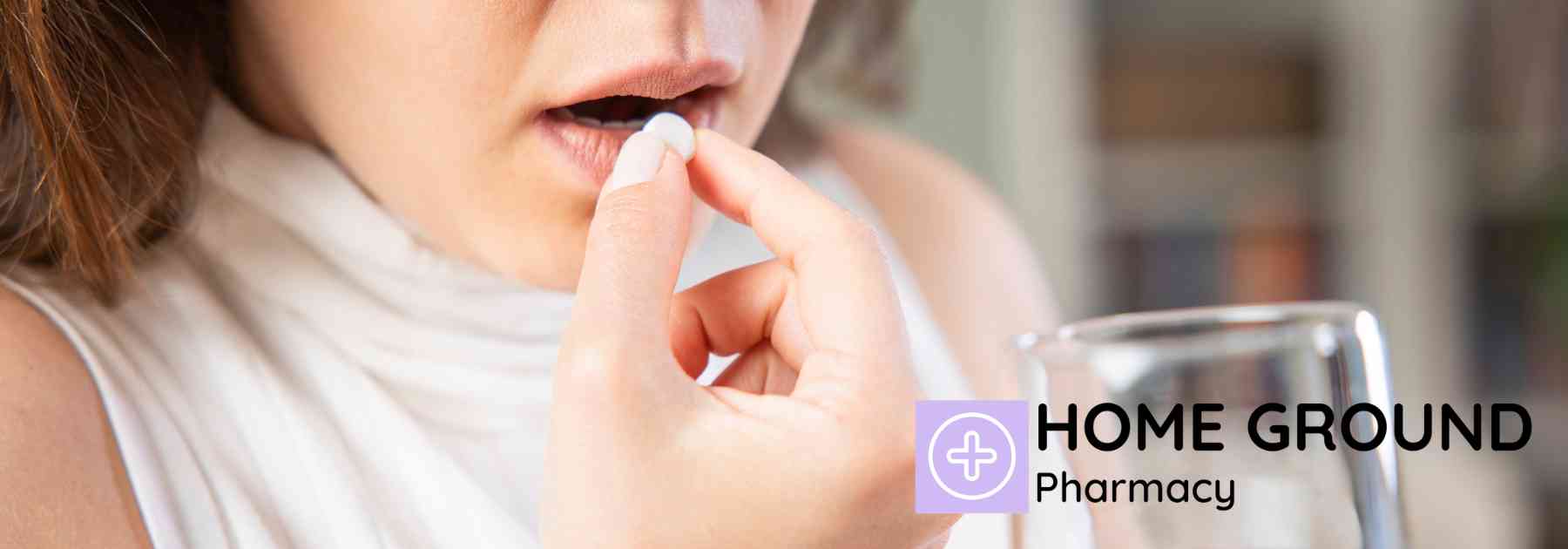 woman holding glass of water taking white pill