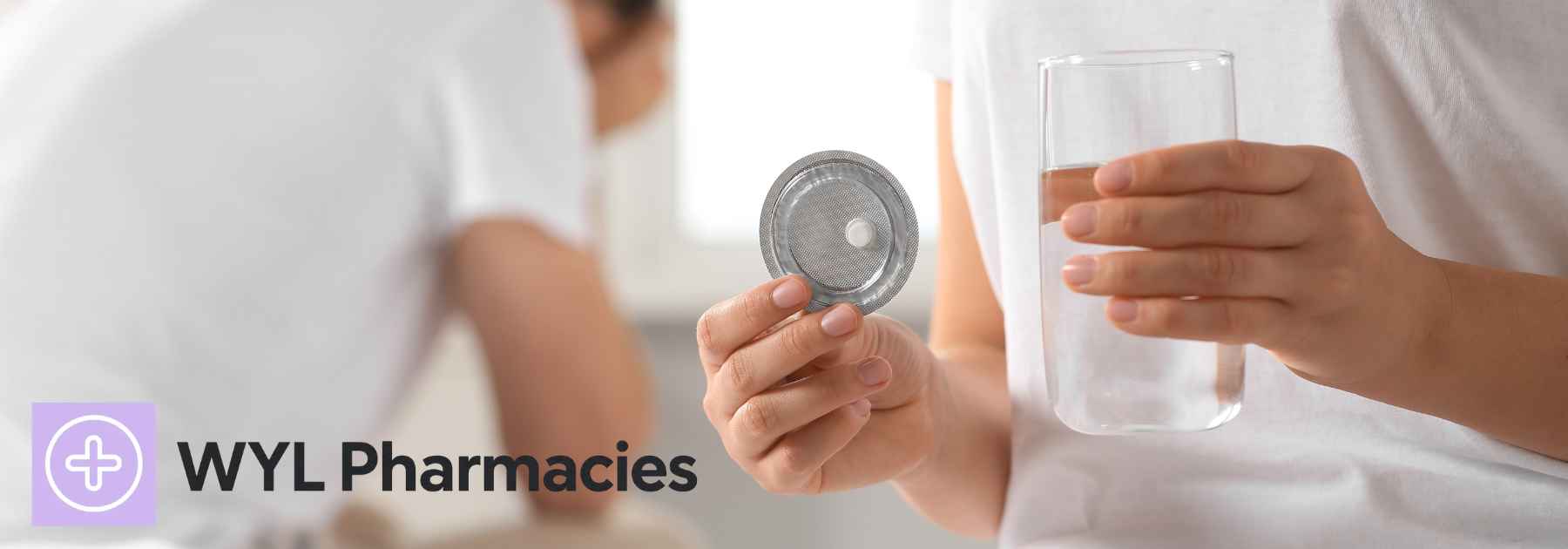 woman holding contraceptive pill and glass of water with male partner in background
