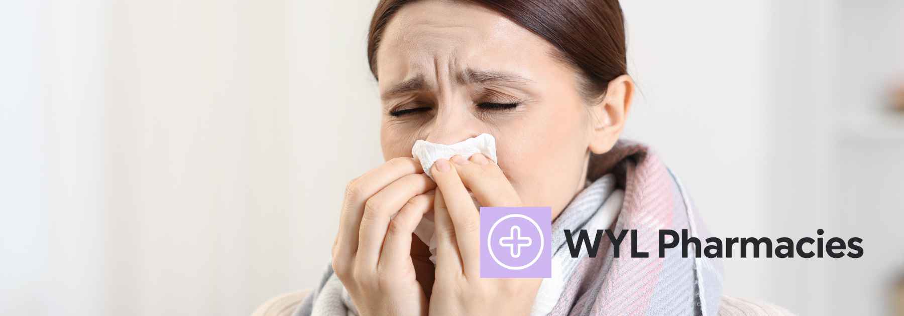 woman wearing scarf blowing her nose with a tissue